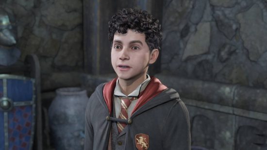 Hogwarts Legacy characters - Lucan Brattleby is talking to the player who is standing offscreen. Lucan is standing next to a pot and a suit of armour.