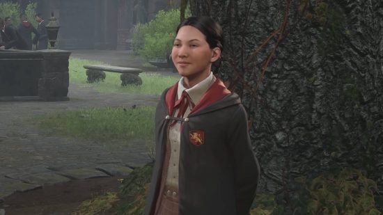 Hogwarts Legacy characters - Nellie Oggspire is standing next to a tree. She is a Gryffindor student.