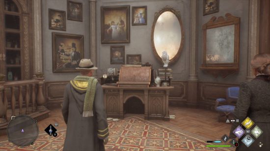Hogwarts Legacy Room of Requirement - the Desk of Description with an owl perched on top. It has a bookrest and a magnifying glass, as well as a cup of tea. Paintings are haphazardly displayed behind it.