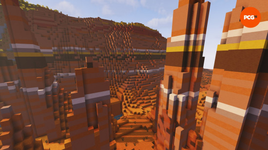The sun illuminates the orange badlands Minecraft biome, with its red sand and yellow, brown, and orange terracotta.