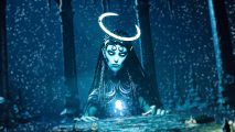A giant, blue angelic-like woman with a lit halo above her had stands before a starry sky