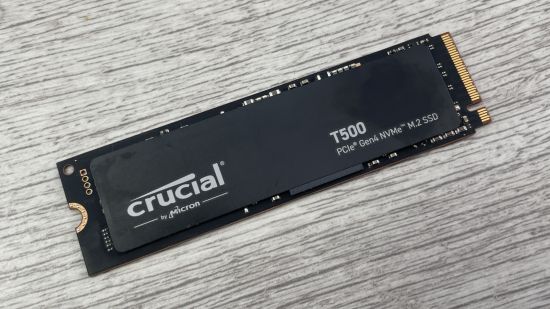 A black Crucial T500 SSD on a wooden laminate surface
