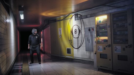 A chubby, grey-haired man stands in the corridor of a hospital, looking at an ominous symbol painted on the wall.